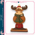 A wooden moose figurine wearing a green scarf and red boots, standing on a wooden base.