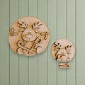 two wooden cutouts of reindeer, one larger and one smaller, both holding candy canes and holly leaves.