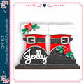 A pair of red and white Santa Claus boots with the word "Jolly" written on them, decorated with red berries and green leaves.