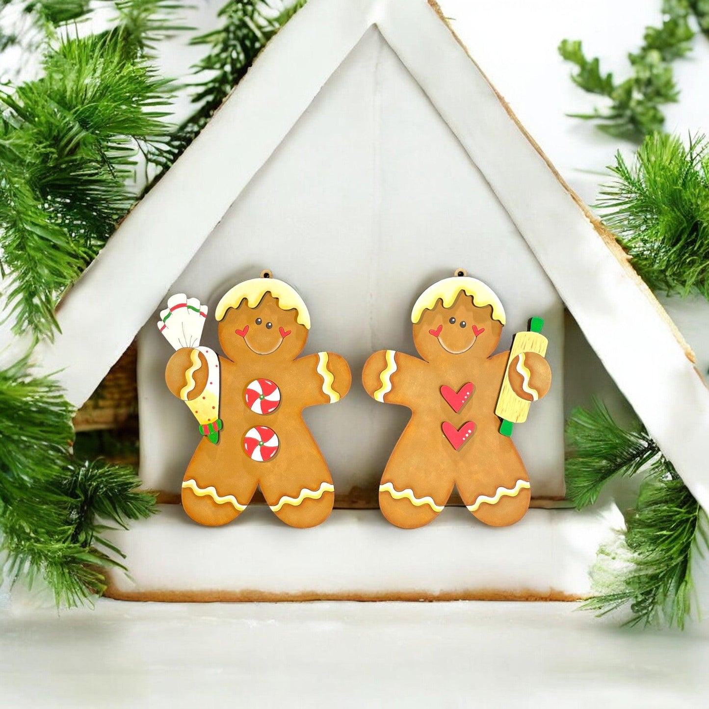 a couple of gingerbread men standing in front of a ginger house