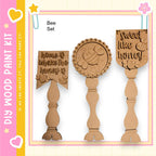 three wooden paint brushes with unique designs and text on them.