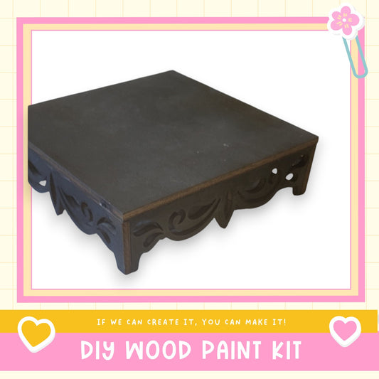 a black wooden table with a decorative design on the legs, presented within a pink and white frame.