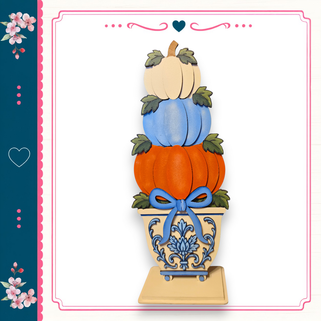 A decorative arrangement of three stacked pumpkins in a vase, with a blue bow tied around the vase.