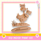 a DIY wood paint kit, including a wooden duck holding an American flag, set against a pink and yellow background.