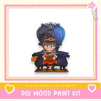 A wooden doll with a witch hat and a book in her hand, sitting on a purple chair.