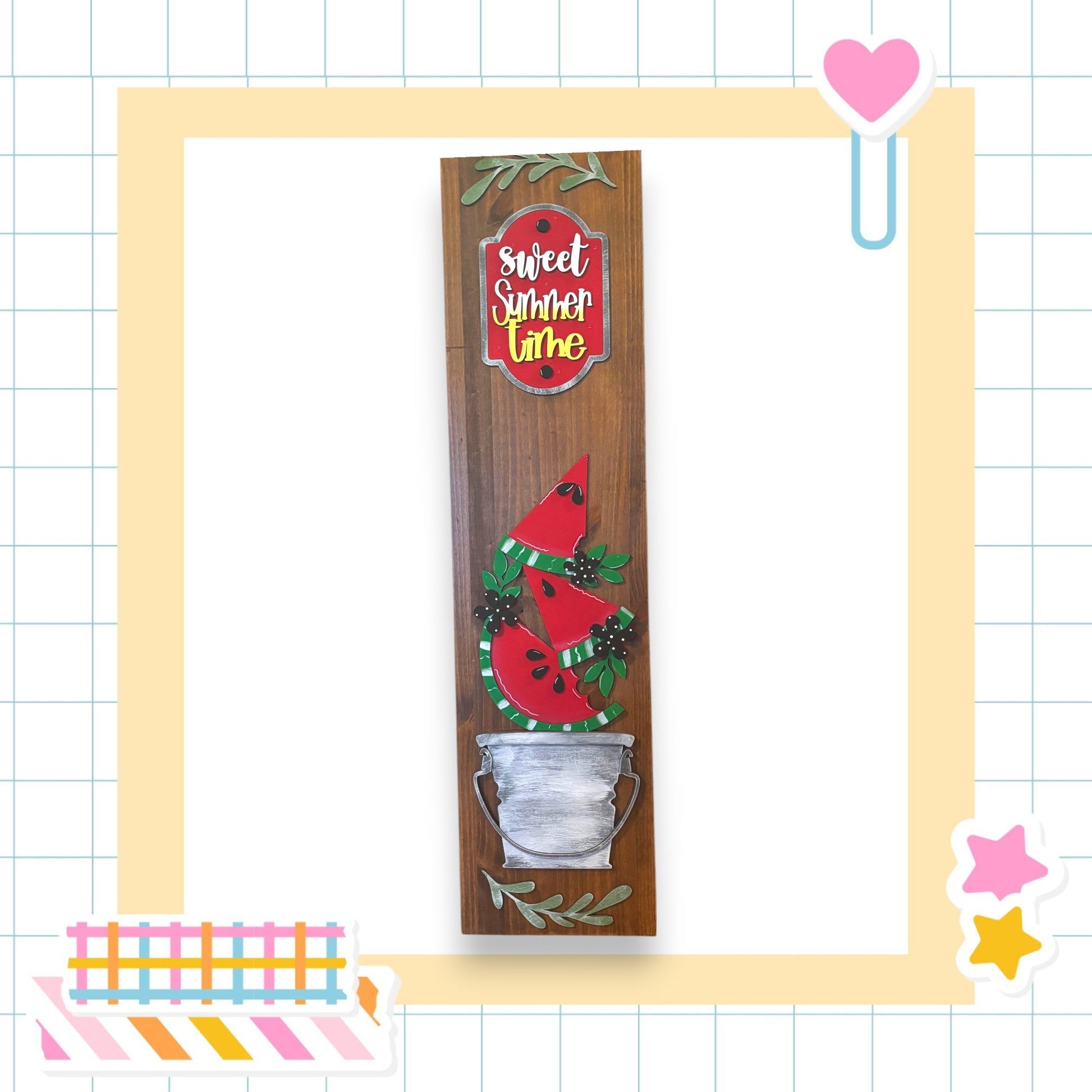 a wooden sign with a watermelon design, surrounded by decorative elements such as a heart, stars, and a striped border.