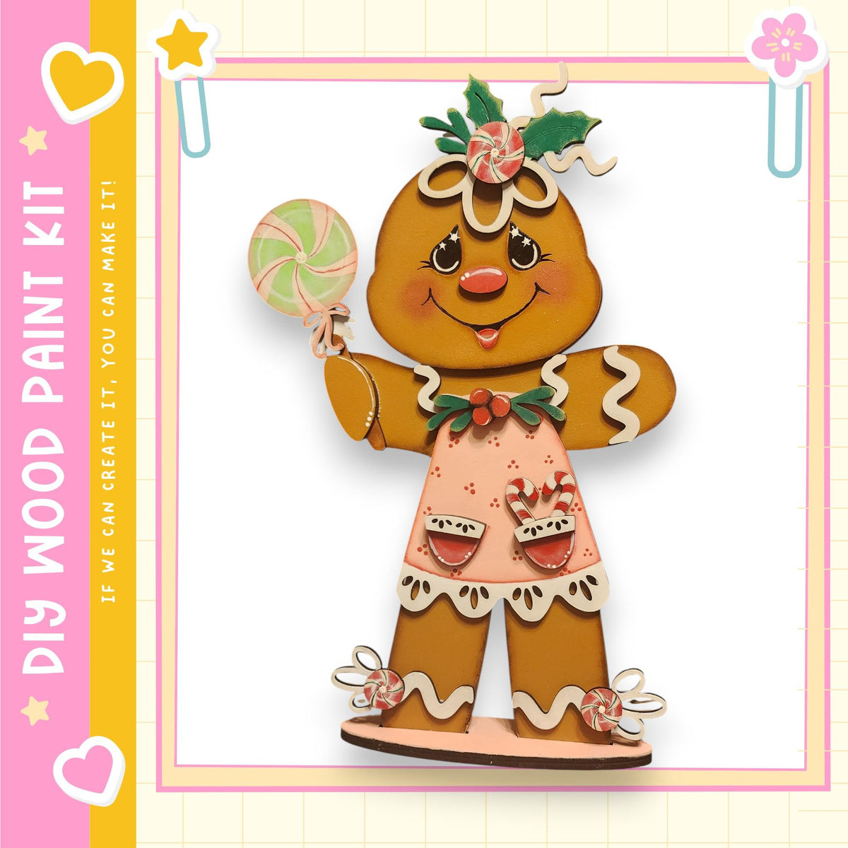 A wooden gingerbread woman figure holding a lollipop and wearing a pink dress with a bow, set against a pink and yellow background with decorative elements.