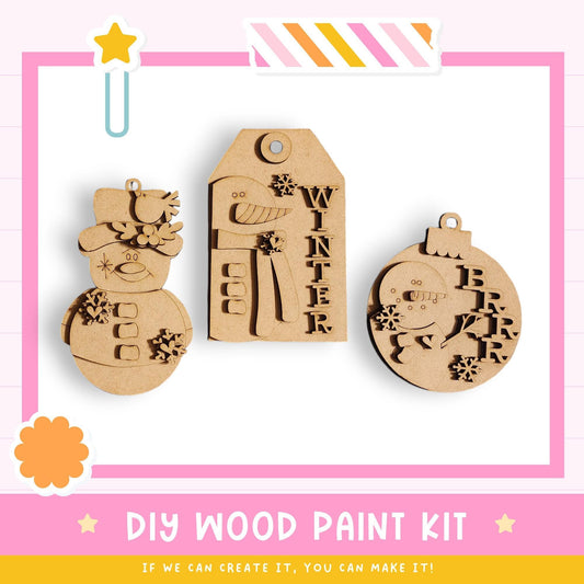 three wooden ornaments, including a snowman, a winter-themed ornament, and a Christmas ornament, displayed against a pink background.