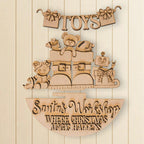 A wooden sign with the text "Toys" and "Santa's Workshop Where Christmas Magic Happens" carved into it, along with various toys and decorations.