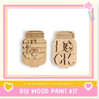 two wooden mason jars with various designs carved into them, including a clover and the letters "LK". The jars are displayed against a pink and yellow background, and there is text at the bottom of the image that reads "DIY WOOD PAINT KIT" and "IF WE CAN CREATE IT, YOU CAN MAKE IT!".