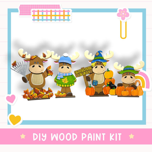 The image is a colorful illustration featuring four cartoon moose characters dressed in fall-themed outfits, including hats and scarves, standing next to a pile of autumn leaves and pumpkins.