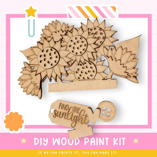 The image is a DIY wood paint kit featuring a wooden flower design with sunflowers and leaves. The kit includes a wooden frame and a wooden paintbrush, along with a wooden tag that says "Find the sunlight". The kit is presented in a pink and white color scheme, and the text encourages creativity and the ability to create the kit.