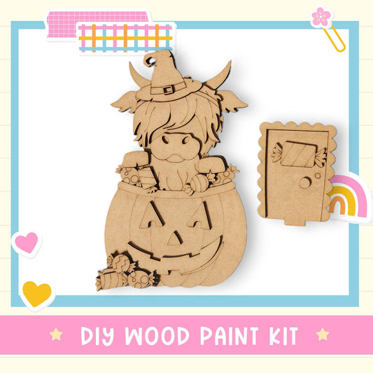 The image is a DIY wood paint kit featuring a wooden pumpkin with a carved face and a witch hat, along with a small wooden door and a heart-shaped sticker.
