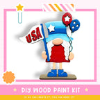 a wooden gnome figure holding a flag with the word "USA" written on it, along with two red and blue balloons. The image also includes a DIY wood paint kit and a message encouraging creativity.