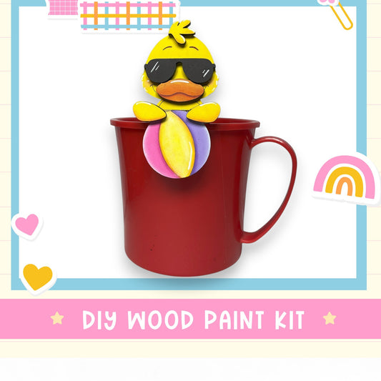 A red mug with a yellow duck wearing sunglasses, surrounded by various colorful stickers and hearts, with the text "DIY WOOD PAINT KIT" displayed.