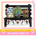 The image is a DIY wood paint kit featuring a wooden bench with a decorative peacock design, flowers, and a banner. The text on the image encourages creating art and says, "If we can create it, you can make it!"