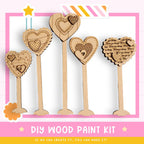 a DIY wood paint kit with five wooden heart-shaped objects, each with a unique design and pattern. The kit appears to be made of wood and is designed for painting. The kit is presented in a pink and white color scheme, with a star decoration on the top left corner. The text "DIY WOOD PAINT KIT" is prominently displayed, along with the phrase "IF WE CAN CREATE IT, YOU CAN MAKE IT!" at the bottom of the image.