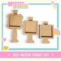 three wooden frames, each with a blank space inside, arranged in a row. The frames appear to be made of cardboard and are designed to be used as photo frames. The image also includes a text overlay that reads "DIY WOOD PAINT KIT" and a heart icon, suggesting that the frames are intended for use as decorative items.
