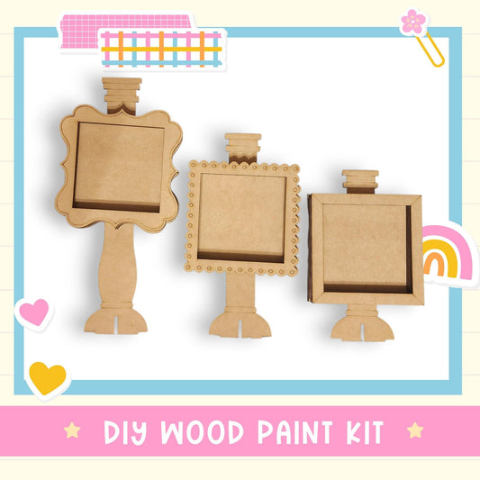 three wooden frames, each with a blank space inside, arranged in a row. The frames appear to be made of cardboard and are designed to be used as photo frames. The image also includes a text overlay that reads "DIY WOOD PAINT KIT" and a heart icon, suggesting that the frames are intended for use as decorative items.