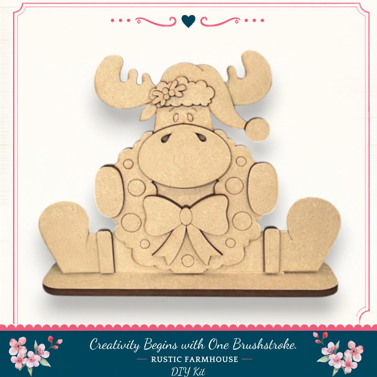 A wooden toy moose wearing a wreath and hat, sitting on a wooden base.