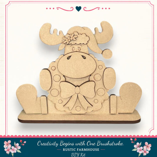 A wooden toy moose wearing a wreath and hat, sitting on a wooden base.