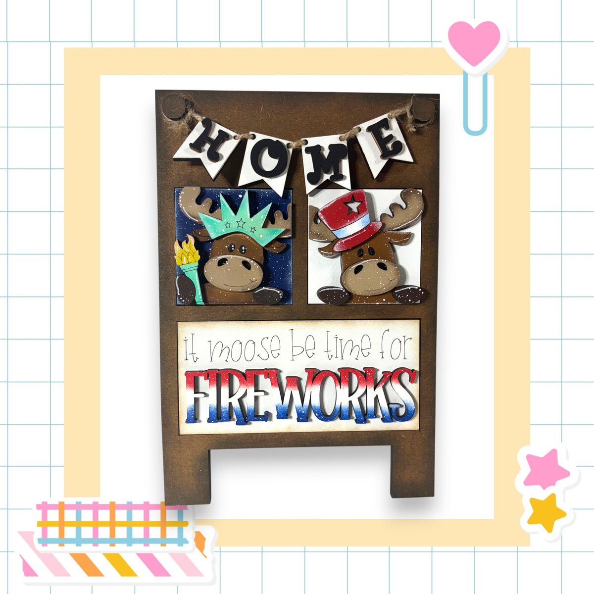 The image is a wooden sign with a moose and a star, featuring the text "Home" and "It moose be time for fireworks" in a playful and festive style.