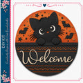 a black cat with large eyes peeking out from behind a circular sign that says "Welcome". The sign is decorated with bats, stars, and a floral border, creating a festive and welcoming atmosphere.