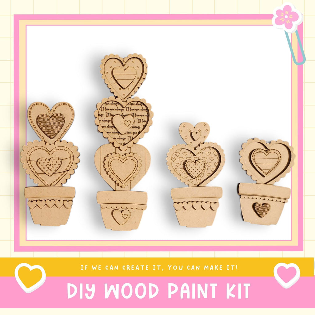 a DIY wood paint kit with four heart-shaped cutouts arranged in a row, each in a pot. The kit appears to be made of cardboard and is designed for creating wooden heart-shaped decorations or ornaments.