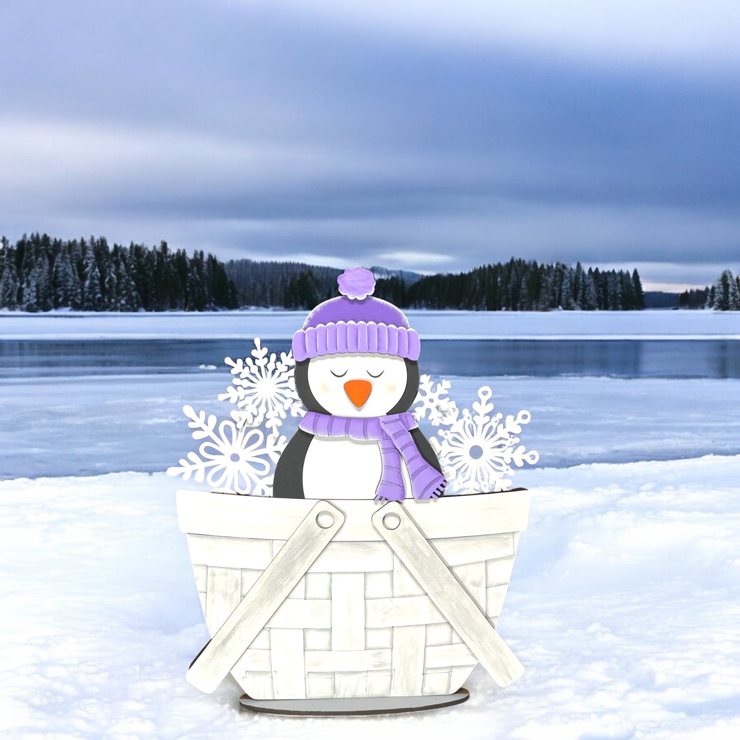 a penguin sitting in a basket in the snow