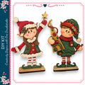 two wooden figurines of Christmas-themed characters, a girl and a boy, dressed in festive attire and holding various holiday decorations.