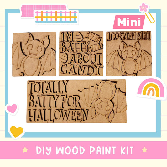 The image is a DIY wood paint kit featuring a bat-themed design. The kit includes a bat-shaped stencil and a sign that says "I'm Bating about Candy". The kit is presented in a colorful and playful manner, with the text "DIY WOOD PAINT KIT" and "MINI" visible.