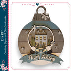 A decorative ornament with a snow globe containing a house and trees, surrounded by snowflakes. The ornament has a ribbon with the text "Happy Holidays" and a heart symbol.