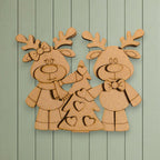A wooden cutout of two cartoon reindeer standing next to a Christmas tree, with hearts on the tree.