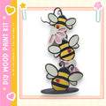 A colorful and whimsical painting kit featuring a playful arrangement of cartoon-style bees on a wooden base.