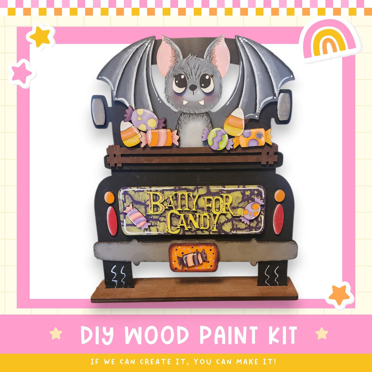 A wooden toy truck decorated with a bat and various candy items, including a sign that says "BABY FOR CANDY". The truck is set against a pink and yellow background with stars and a rainbow.