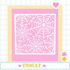 a large square with a pink spider web pattern on it, surrounded by a yellow border. The image is framed by a pink border and includes a heart and two stars as decorative elements. The word "STENCILS" is written in the bottom right corner of the image.