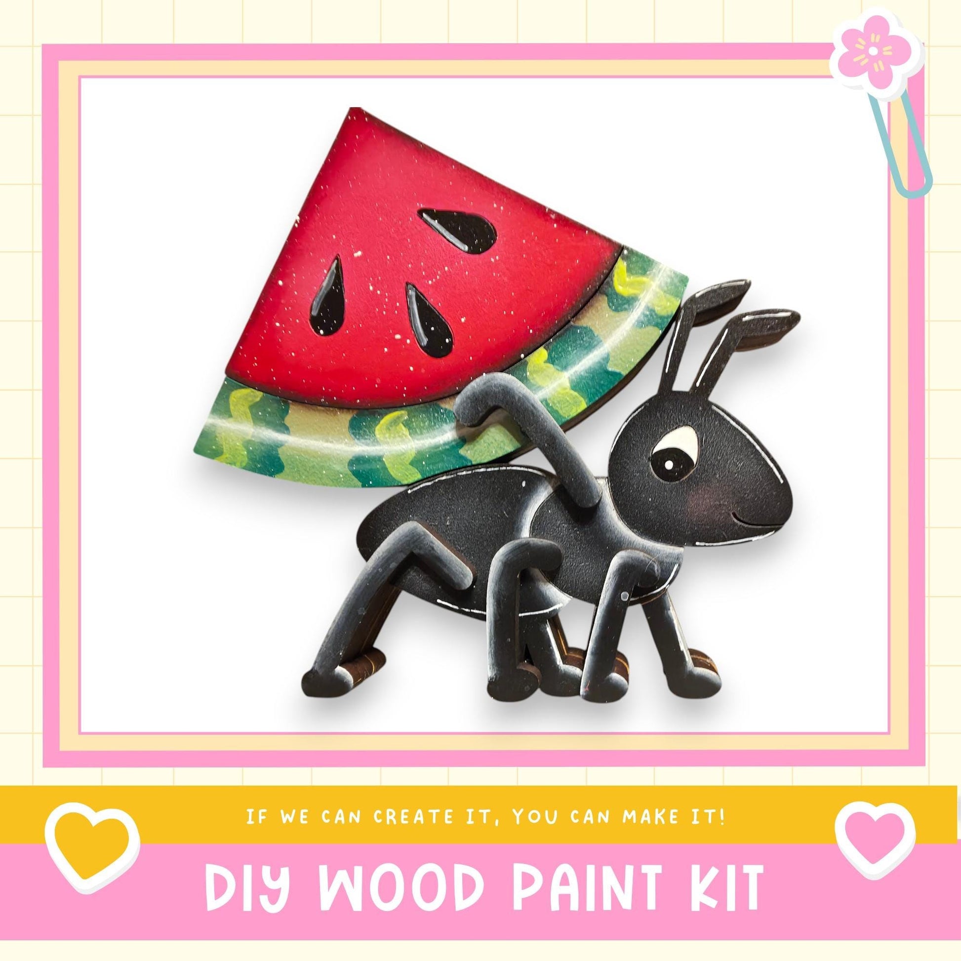The image is a DIY wood paint kit featuring a black ant carrying a slice of watermelon on its back, set against a pink and yellow background.