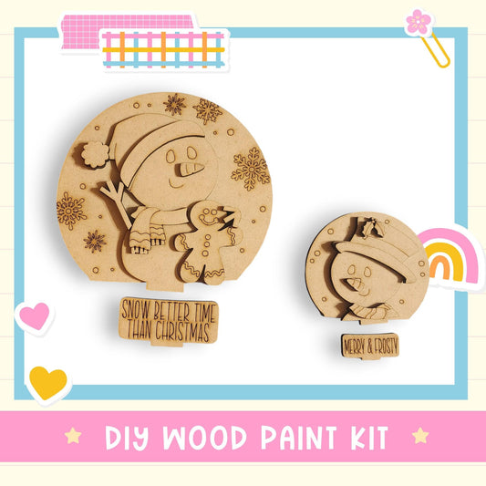 a DIY wood paint kit for creating wooden snowmen and snowflakes. The kit includes two snowman and snowflake designs, along with a sign that says "Snow better time than Christmas".