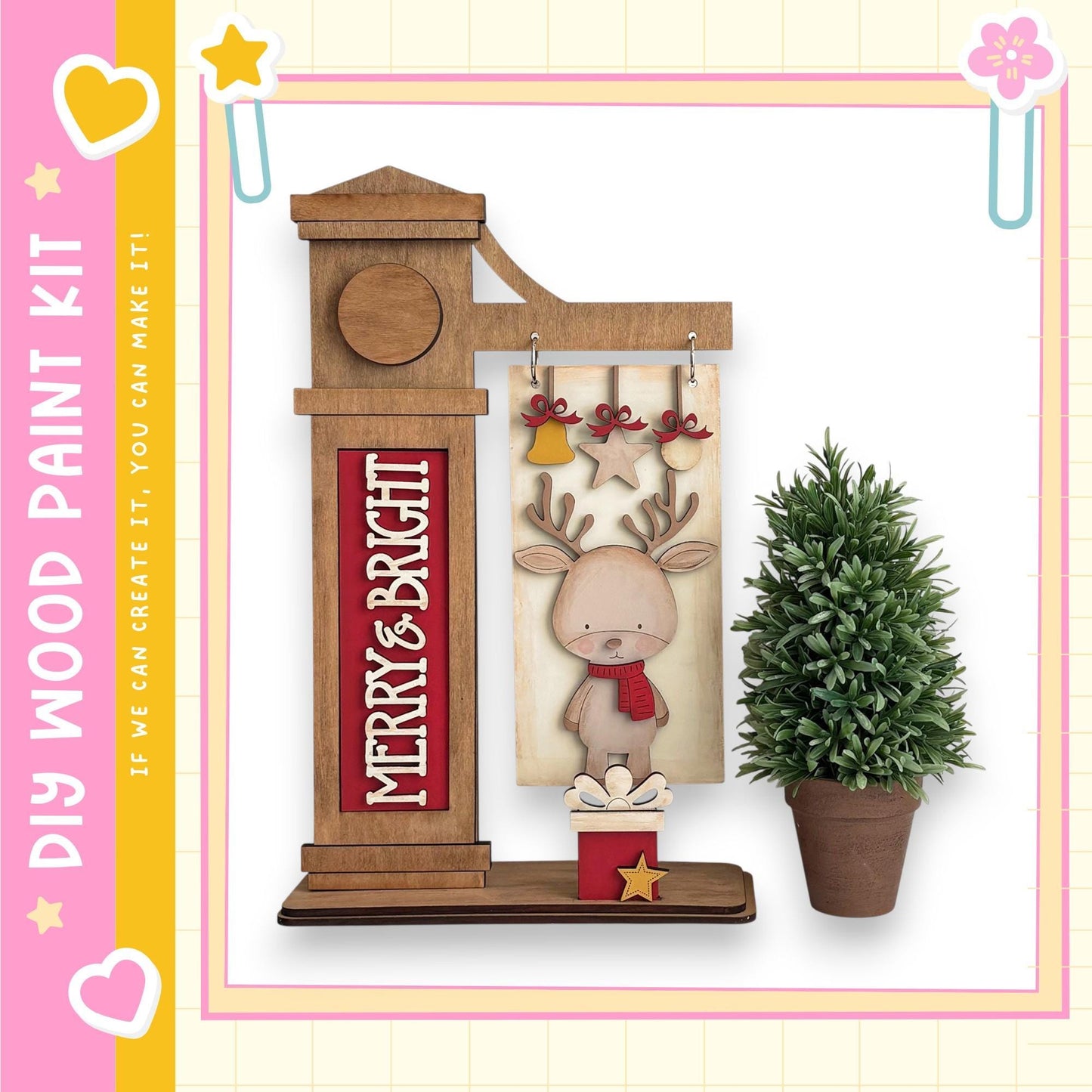 a wooden clock with a deer figure on it, placed next to a potted plant. The clock has a sign that says "MERRY & BRIGHT".