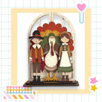 A wooden display featuring a turkey, a boy in a hat, and a girl in a dress, all standing together.
