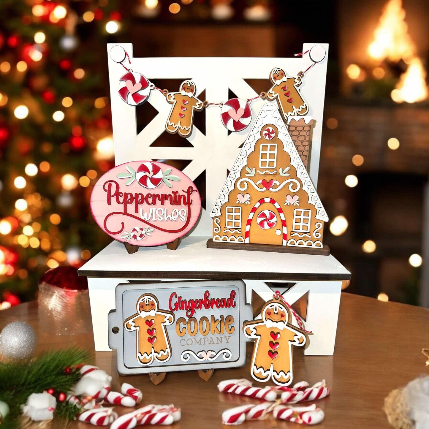 a gingerbread house with gingerbread cookies on a table next to a christmas tree