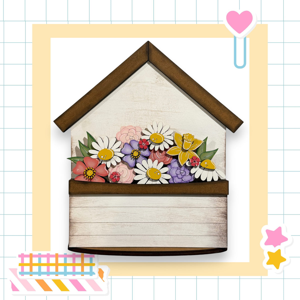 A wooden house-shaped planter filled with a variety of colorful flowers, including daisies, roses, and other blooms.