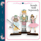 A wooden nutcracker figure holding a sword and a mouse figure, with a ballerina figure in a pink tutu, all standing on a wooden base.