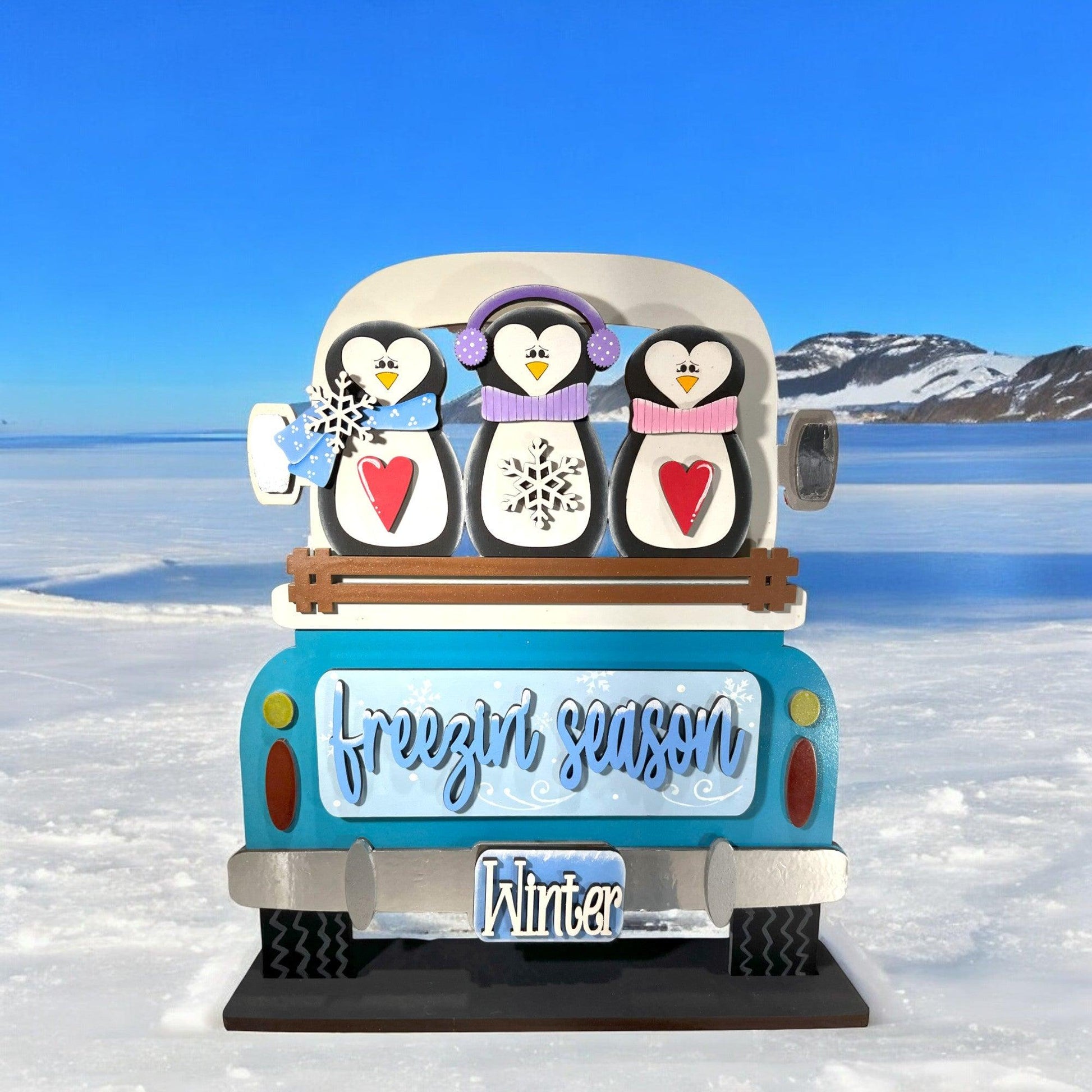 a blue and white bus with three penguins on top of it