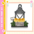 A wooden lantern with a sign that reads "Fresh Roses" is displayed in a vase with yellow roses, surrounded by greenery.