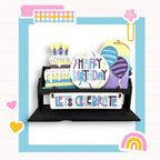 a birthday card with a cake and balloons