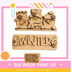 The image is a promotional poster for a DIY wood paint kit for creating winter-themed decorations. It features three wooden snowmen and a snowman-shaped sign with the word "WINTER" written on it.