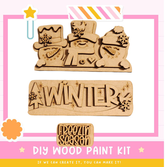 The image is a promotional poster for a DIY wood paint kit for creating winter-themed decorations. It features three wooden snowmen and a snowman-shaped sign with the word "WINTER" written on it.