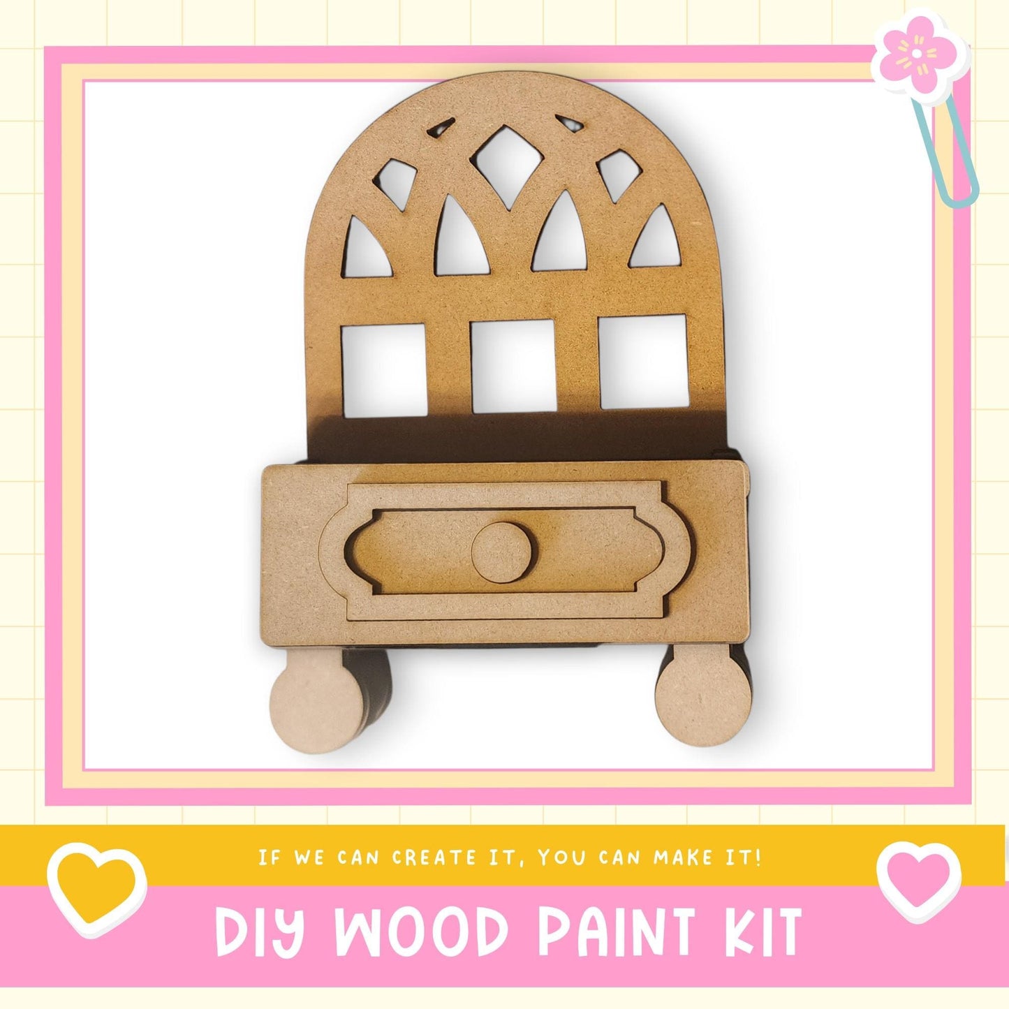 a DIY wood paint kit, with a wooden cabinet or shelf depicted in the center. The kit appears to be made of wood and has a drawer. The image is framed with a pink border and includes a heart symbol on the left side. The text "DIY WOOD PAINT KIT" is displayed at the bottom of the image.