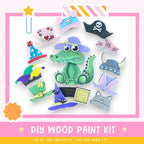 The image is a colorful and playful DIY wood paint kit featuring a green alligator wearing various hats and accessories, including a pirate hat, a top hat, and a cat's hat.